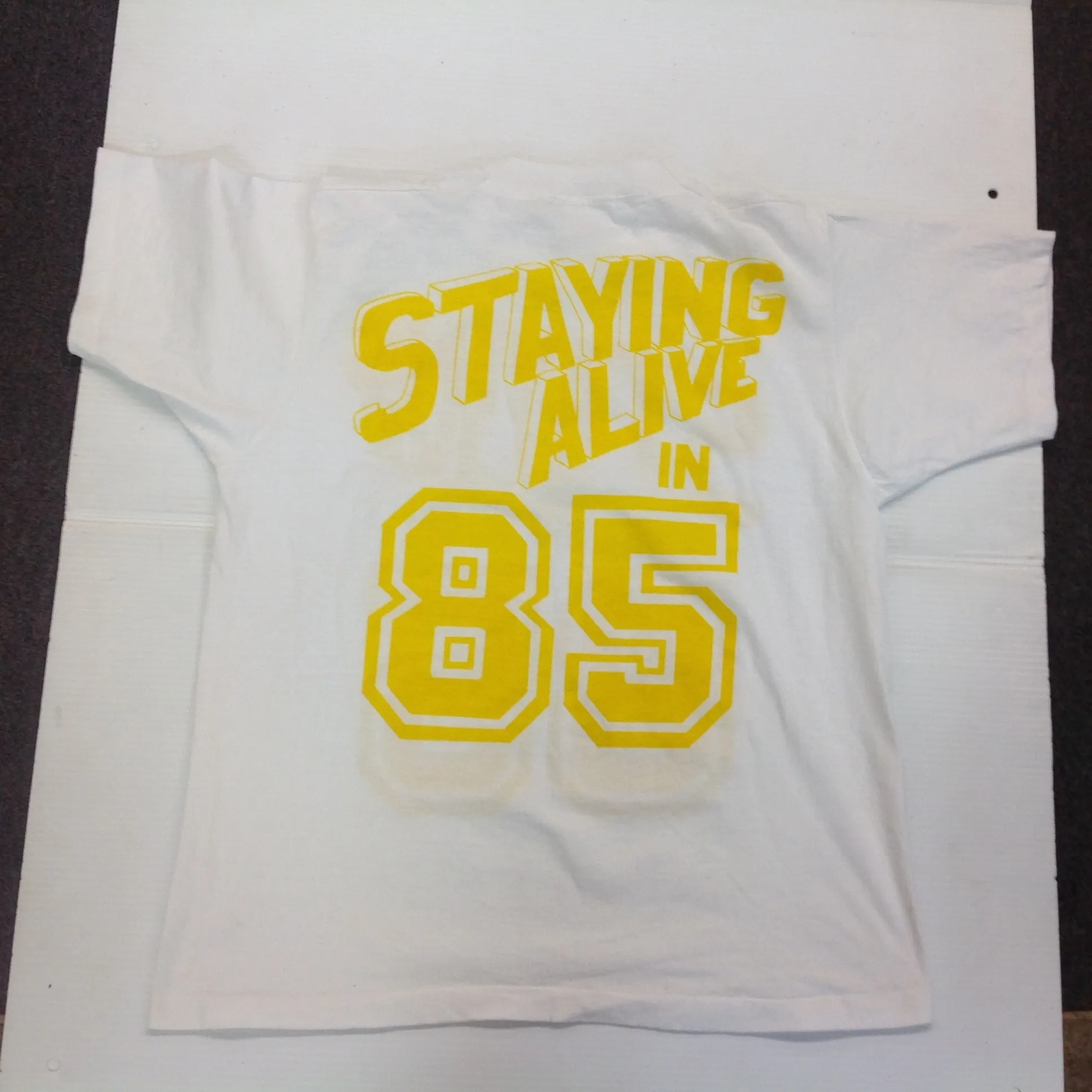 Vintage 1980's Novelty T-Shirt STAYING ALIVE IN 85 Yellow on White Katharine Hamnett