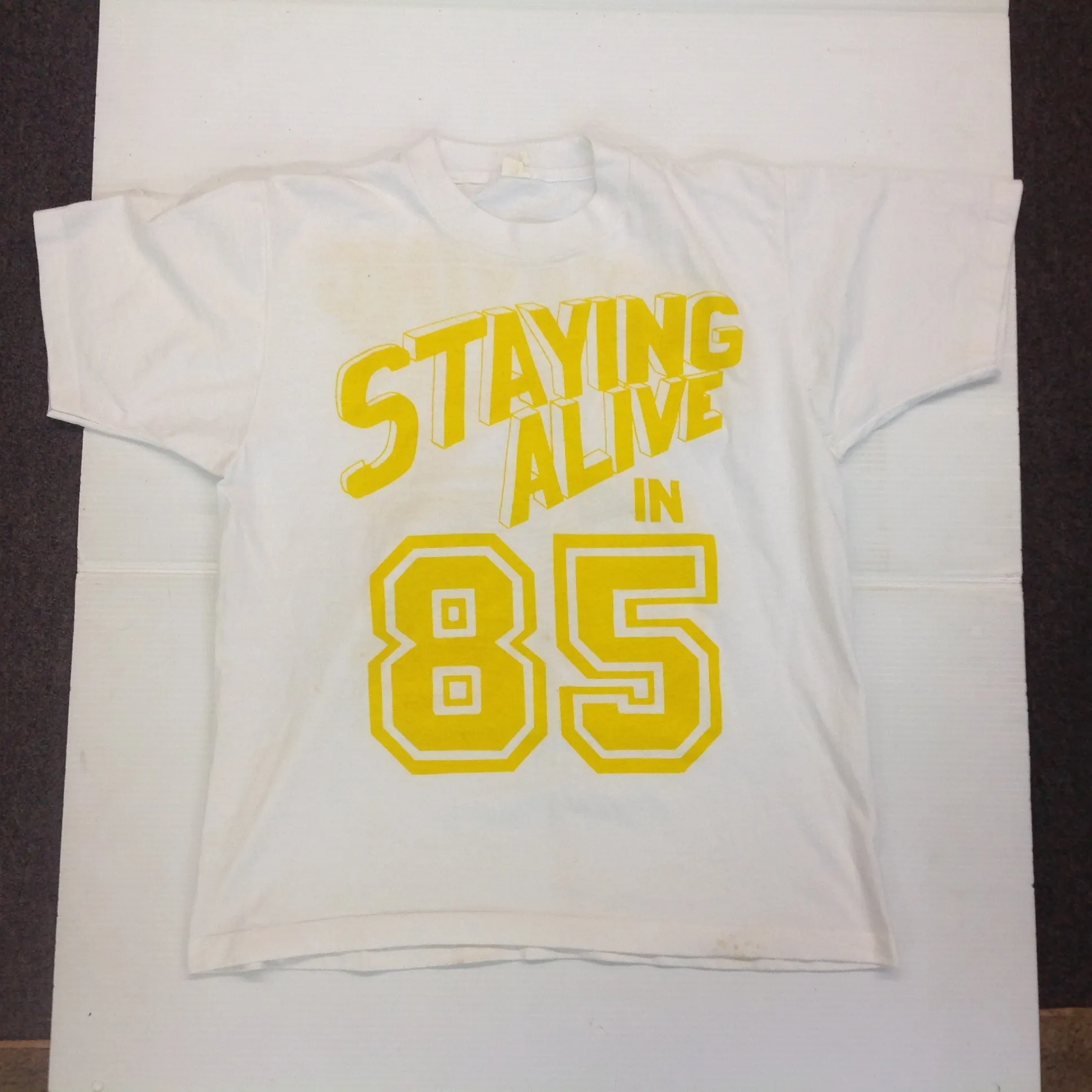 Vintage 1980's Novelty T-Shirt STAYING ALIVE IN 85 Yellow on White Katharine Hamnett